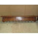 An oak wall mounted hall shelf and combined hat/coat rack with shaped apron and nine cast gilt metal