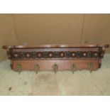 An oak wall mounted hall shelf and combined hat/coat rack with repeating carved and moulded frieze