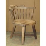 A Arts and Crafts style low beechwood chair with curved turned spindle back over a solid seat raised