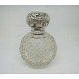 A cut glass globular shaped perfume bottle with embossed silver mounted screw cap