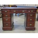 A late Victorian walnut kneehole twin pedestal writing desk with inset faux leather top over the