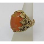 Cabochon fire opal cocktail ring with applied foliate mount, unmarked, tests as 9ct gold, size N,