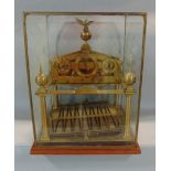 Glass cased Congreve clock, with three dials and rolling ball movement, mounted by an open winged