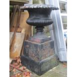 A Georgian style cast iron garden urn, the squat circular and lobbed bowl with flared egg and dart