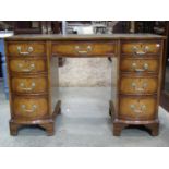 A reproduction Georgian style walnut veneered kneehole writing desk with inset leather green leather