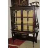 An Edwardian mahogany display cabinet freestanding and enclosed by a pair of glazed panelled doors