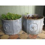 A pair of lead planters of circular form with repeating lions mask relief panels (planted), 42 cm