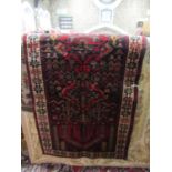 A Persian style wool rug, the black field supporting repeating red ground panels within narrow