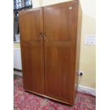 Ercol light elm two door wardrobe, the hinged doors enclosing an interior fitted with a clothes rail