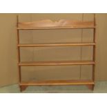 A stripped and waxed pine wall shelf fitted with four tiers within a shaped outline, 85cm wide x