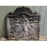A small antique cast iron fire back with raised relief detail (cracked), 51 cm wide x 54 cm in