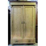 A European stripped pine wardrobe enclosed by a pair of three quarter length rectangular panelled