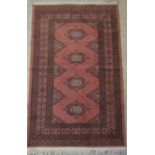 Small cotton rug in the Persian style, pink ground enclosing four medallions within running borders,