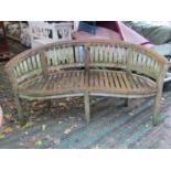 A weathered contemporary teak banana shaped garden bench 150 cm long approx