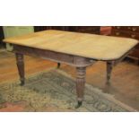A Victorian mahogany extending dining table raised on four turned and fluted support with two