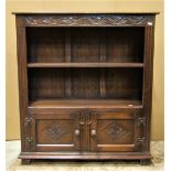 A reproduction old English style oak dwarf bookcase with carved detail, partially enclosed by a pair