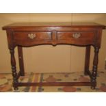A good quality Old English style oak two drawer hall/side table with distressed finish, raised on