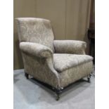 A Victorian easy chair with rolled arms, sprung seat and upholstered finish, raised on turned