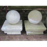 A pair of composition stone pier caps with sphere finials, the caps 43 cm square x 50 cm in height