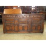 A good quality reproduction Jacobean oak dresser base enclosed by three panelled and fluted doors