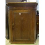 A 19th century oak hanging corner cupboard enclosed by a rectangular moulded panelled door with