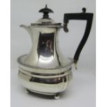 A Georgian style silver coffee pot with gadrooned borders, raised on ball feet, with ebony handle