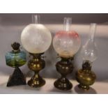 A collection of four Victorian and later oil lamps, three in brass, the fourth with a cast iron base