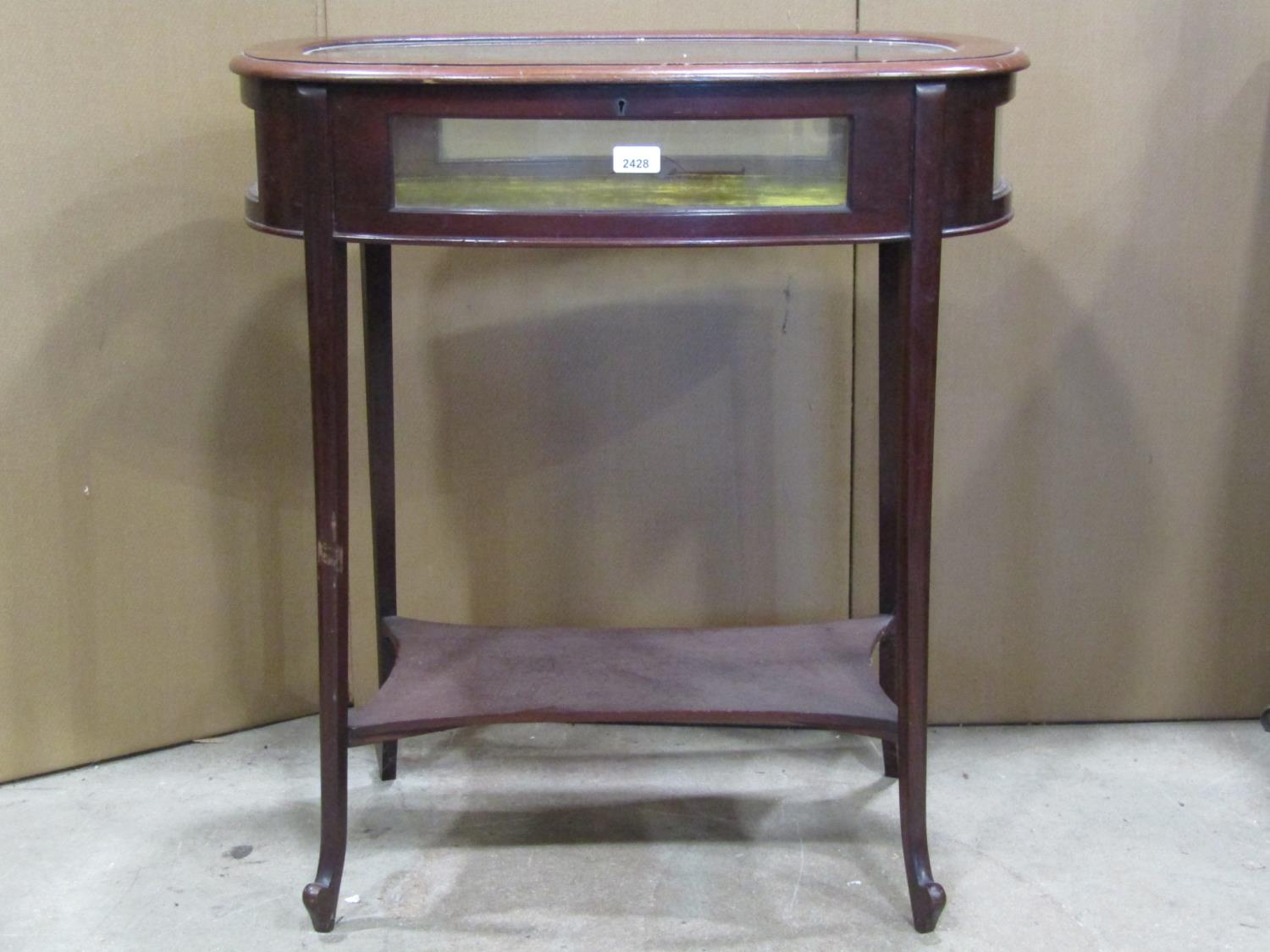 An Edwardian mahogany vitrine, body of oval form with glass top and side panels raised on four swept