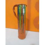 Possibly by Brannam of Barnstaple a large tall terracotta jug with plaited handle and drip glaze,