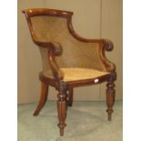 A Regency mahogany bergere library chair, the carved frame with scrolled and other detail, raised on