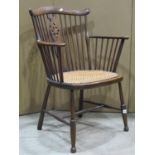 An Edwardian Windsor stick back elbow chair with wheel back splat, cane work seat on turned supports