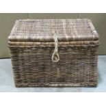 A rectangular wicker basket with thong strapped hinged lid