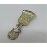 A Victorian silver caddy spoon with embossed bell shaped bowl showing fruiting vines, the scrolled