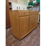 Ercol light elm tall sideboard, fitted with three drawers over three cupboard doors, enclosing a