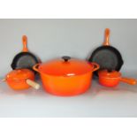A collection of burnt orange Le Creuset cookware comprising two skillet type pans, two small