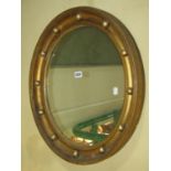 A Regency gilt framed wall mirror of oval form with ball surround within a deep moulded frame 59