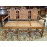 A Victorian oak three seat sofa, loosely in the carolean style, with cane panelled seat and back