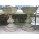 A pair of weathered three sectional composition stone garden urns with octagonal shaped shallow