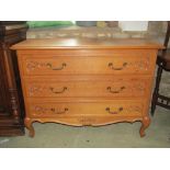 A medium to light oak three drawer commode, with carved foliate and moulded detail, brass drop