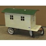A painted wooden model of a showman's caravan with hinged roof and door openings, together with a