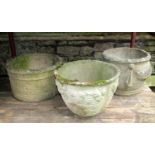 Three weathered composition stone planters of varying design with raised relief detail