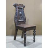 A Victorian carved oak hall chair, the panelled back with green man, lion mask and scrolling