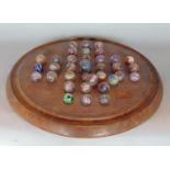 A Victorian mahogany solitaire board housing a collection of Victorian swirled glass marbles