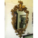 A shield shaped wall mirror, the scrolling gilt moulded and acanthus frame with raised flower and