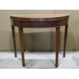 A Georgian mahogany demi-lune fold over top tea table raised on four square tapered legs and spade