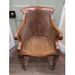 A late regency bergère library chair with scrolled arms, cane panelled frame, raised on turned and