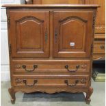 A medium to light oak dwarf side cupboard, partially enclosed by a pair of arched fielded panelled