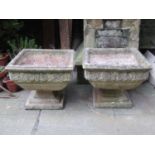 A pair of weathered contemporary composition stone two sectional garden urns of square cut and