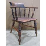 A Windsor smokers bow elbow chair, principally in elm, with turned spindle back over a saddle shaped