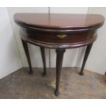 A Georgian mahogany demi-lune fold-over top tea table with enclosed centre, raised on four carved